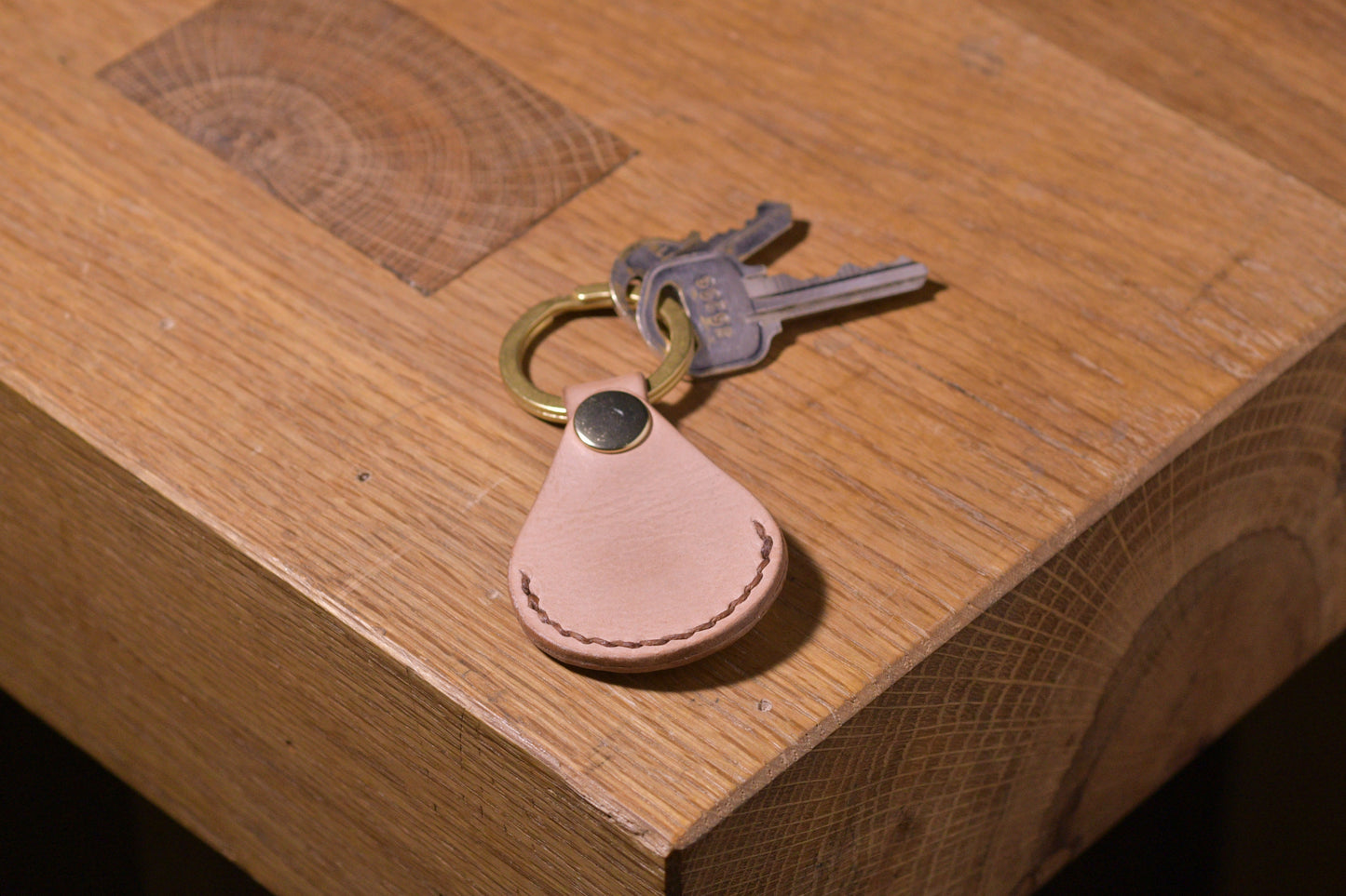 AirTag holder with brass keychain ring, natural veg tan leather, hand made (front shot with keys attached, empty)