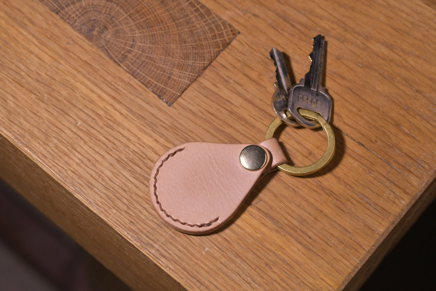 AirTag holder with brass keychain ring, natural veg tan leather, hand made (front shot with keys attached, empty, alt.)