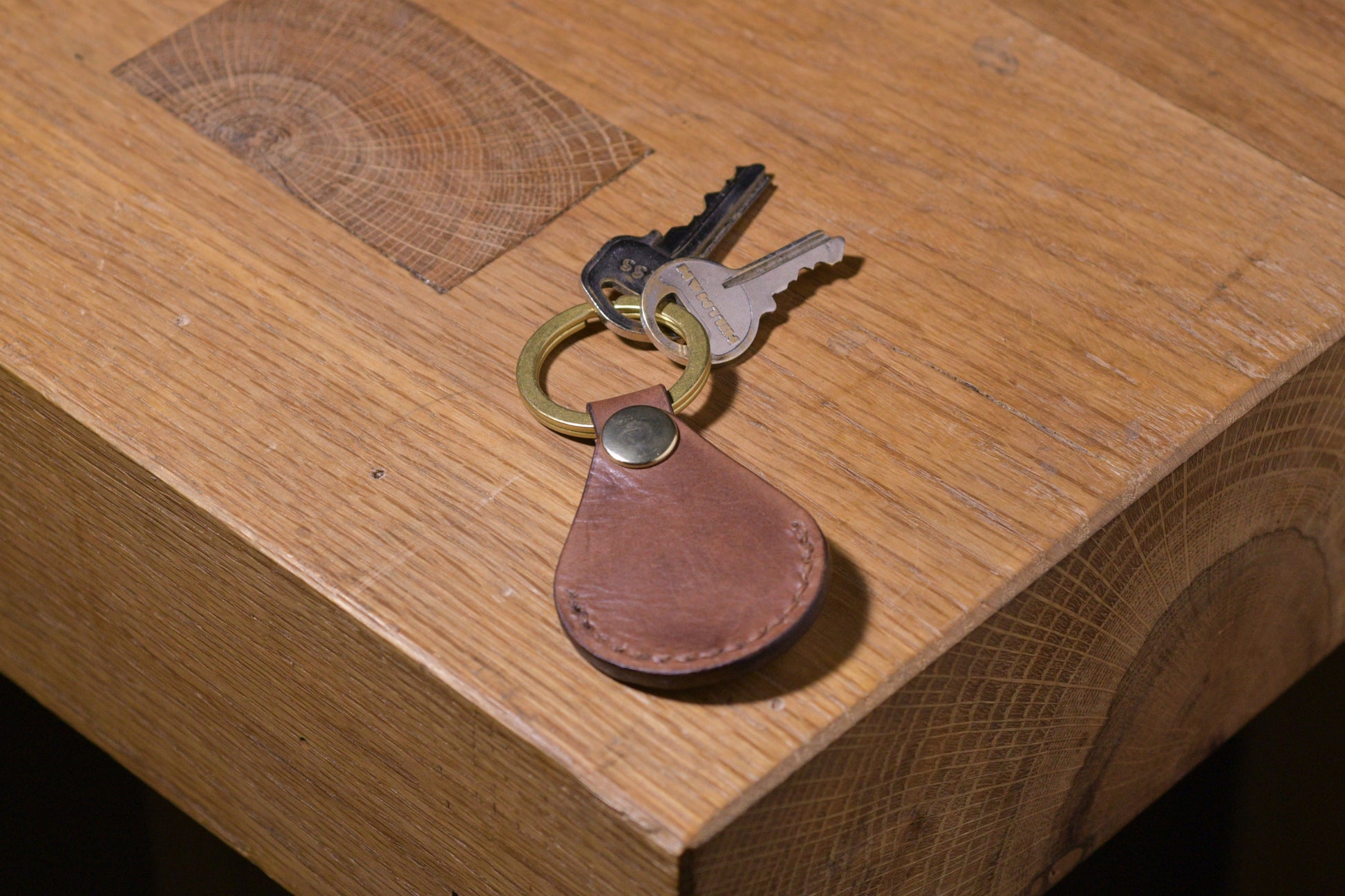 AirTag holder with brass keychain ring, brown veg tan leather, hand made (front shot with keys attached, empty)