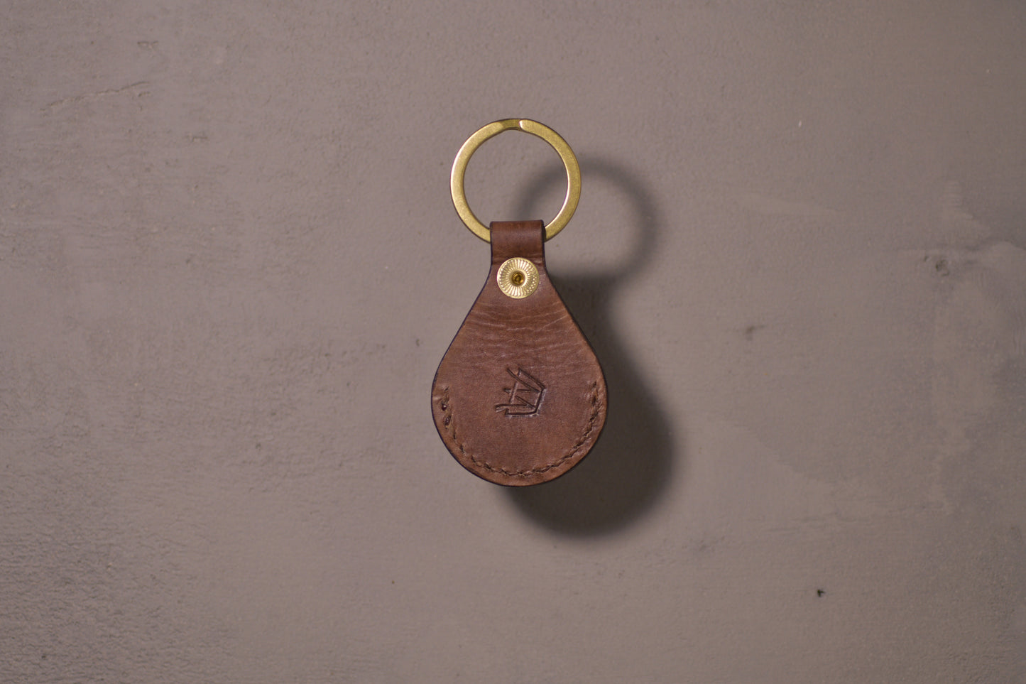 AirTag holder with brass keychain ring, brown veg tan leather, hand made (back side with logo)