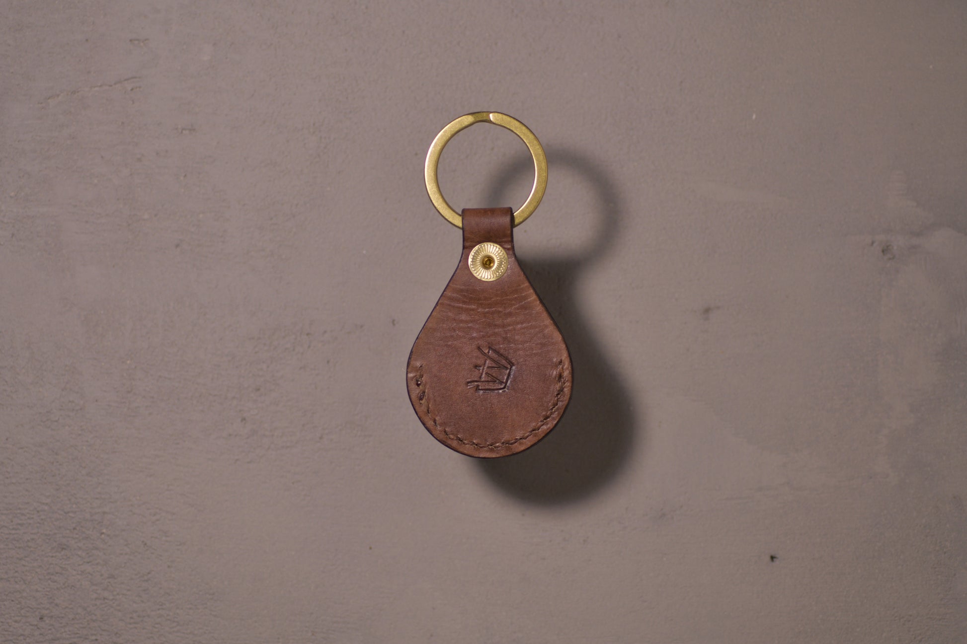 AirTag holder with brass keychain ring, brown veg tan leather, hand made (back side with logo)